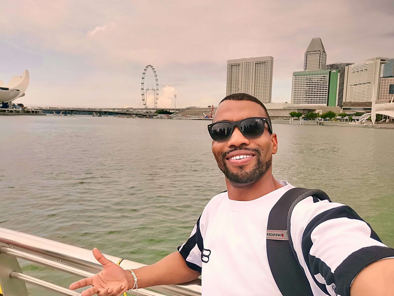 Mounir at the Singapore waterfront, with the Singapore Flyer and city skyline behind him